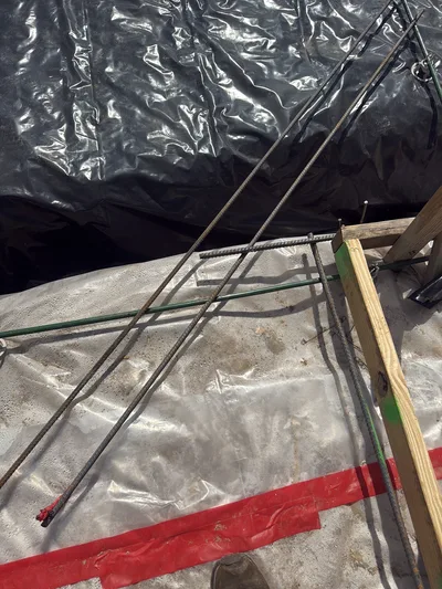Rebar dowels crossing at a foundation edge form before a concrete pour.